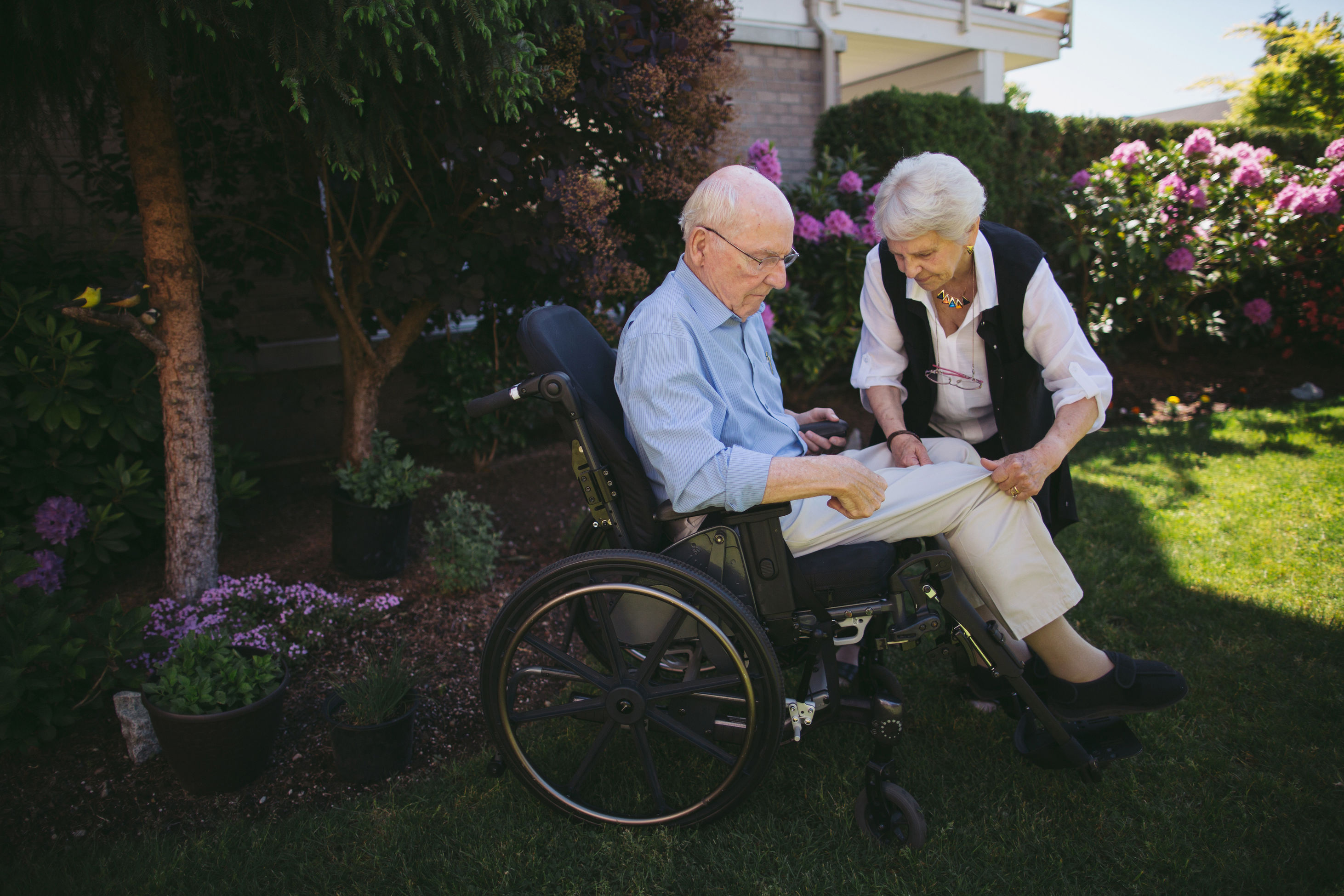 Ältere Frau hilft behindertem Ehemann im Rollstuhl
